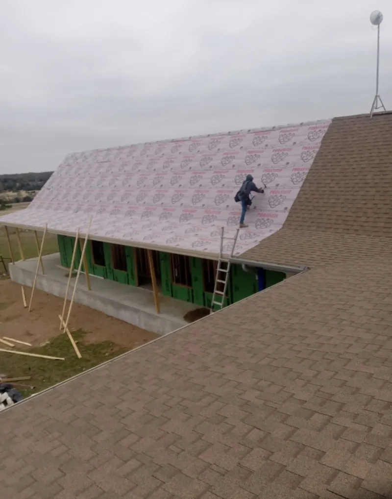 Worker preparing underlayment for a metal roof installation in North Star